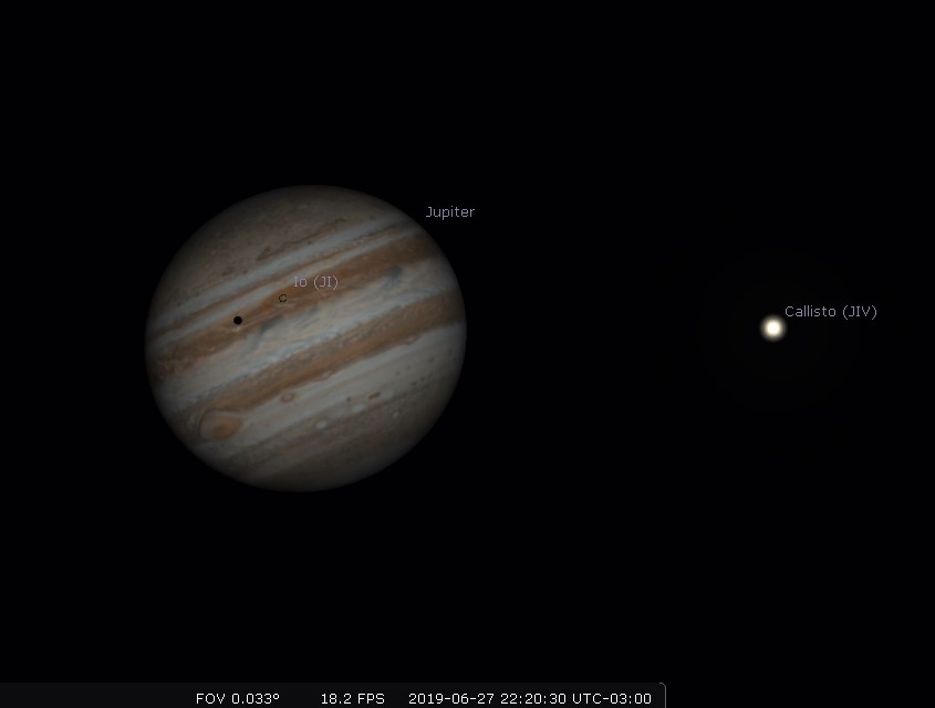 Photo of the planet Jupiter with the shadow of the moon lo crossing over the surface.
